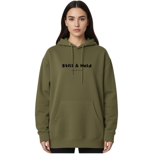 Person wearing a green hoodie with 'Still & Held' branding on a white background